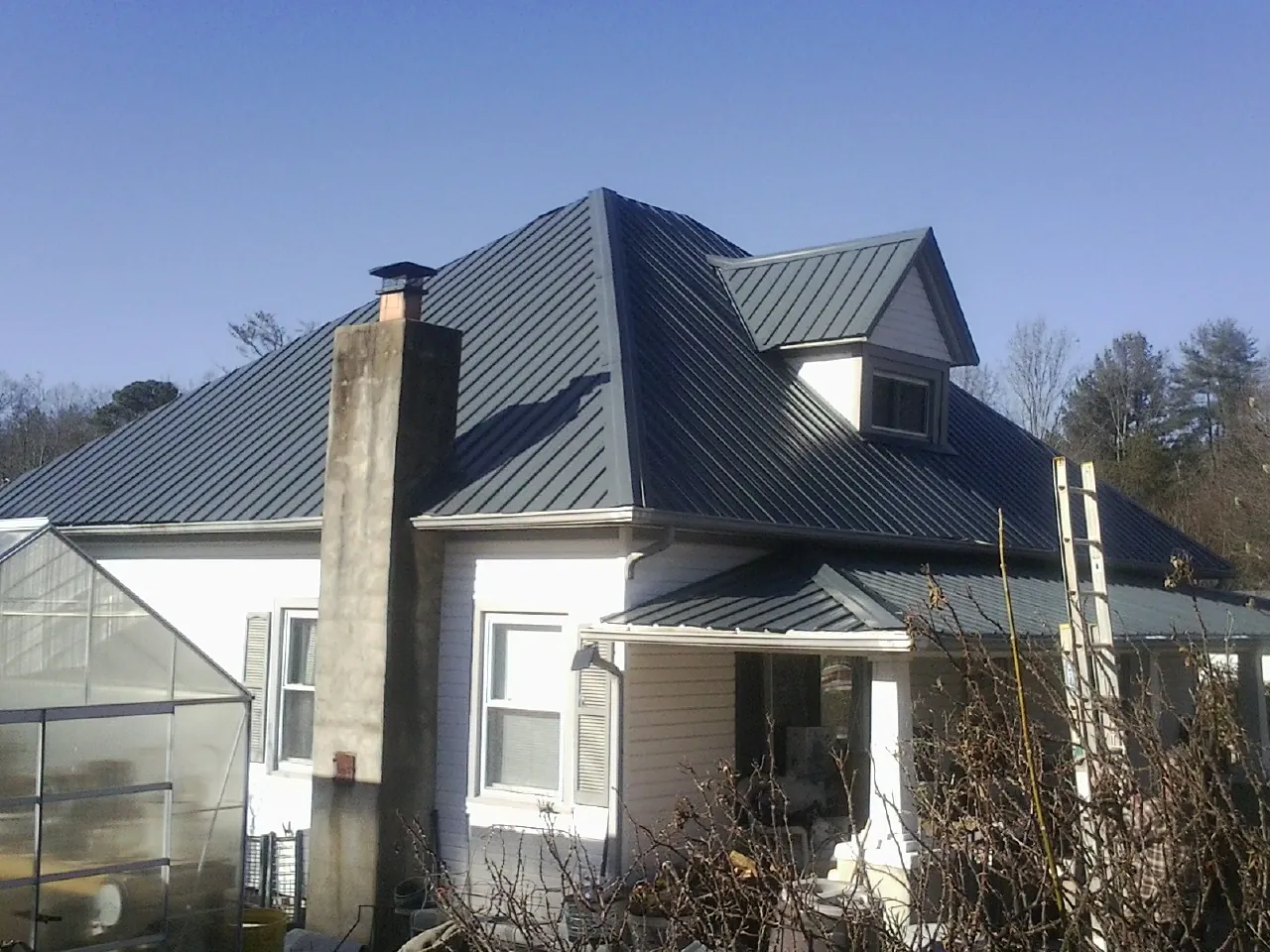 Dark blue standing seam metal roof on a white farmhouse with dormer — Slate & Tile Roof Repair by Roofing Brothers in Ashtabula