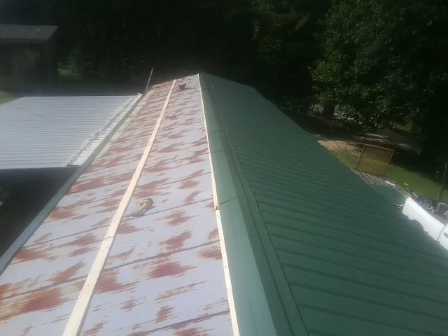 Old rusted panels beside newly installed green metal roofing — Wind Damage Roof Repair by Roofing Brothers in Ashtabula