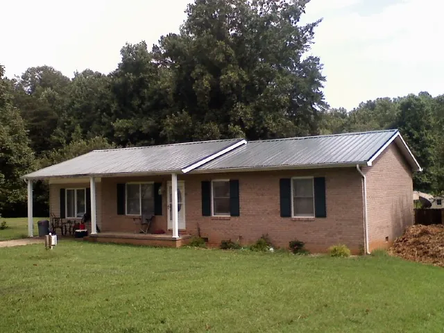 Gray metal roof on a brick ranch house with a side carport in Ashtabula