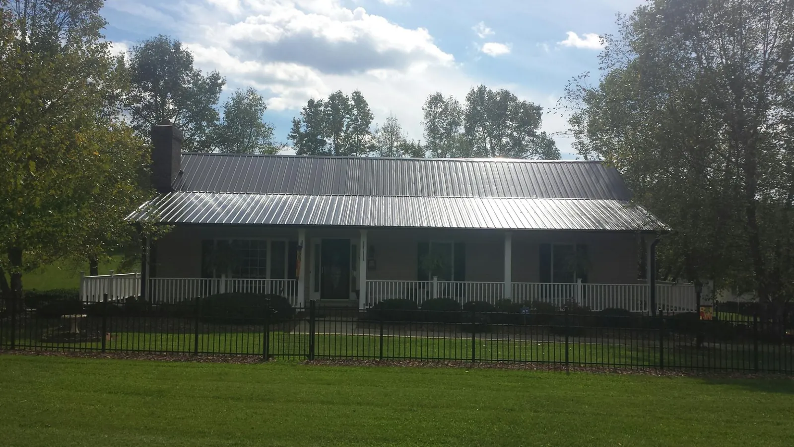 Gray metal roof on a brick ranch with a full width front porch — Gutter Guard Installation work by our crew in Ashtabula