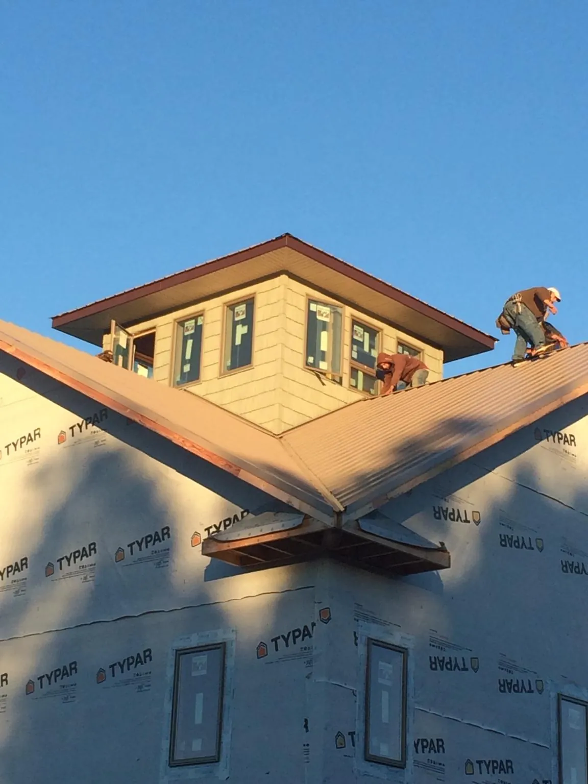 Roofers working around a rooftop cupola on a new metal roof at sunset — Roof Waterproofing in Ashtabula by Roofing Brothers